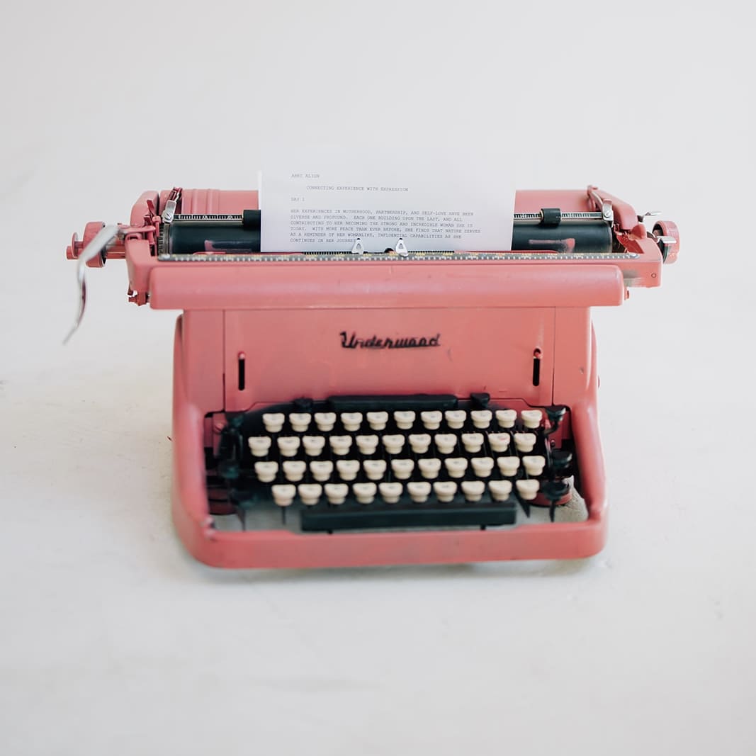 A pink typewriter sitting on top of a table.